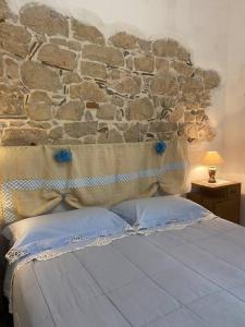 Posto letto in camera con parete in pietra. di Window on the Ogliastra apartment in Baunei a Baunei