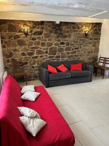 un divano rosso in un soggiorno con parete in pietra di GITE INDEPENDANT en duplex proche mer COTE DE GRANIT ROSE a Pleubian