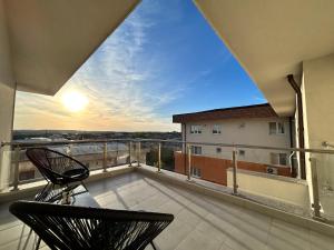a balcony with two chairs and a view of the sunset at 1 Mai - Luxury Park Apartments - Self Check-in - Private parking - 1 in Craiova