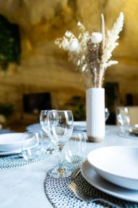 una mesa con vasos y platos y un jarrón con flores en Le temps suspendu, Suite troglodyte & SPA privé, en Doué-la-Fontaine