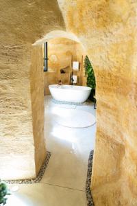 ein Badezimmer mit einer Badewanne in einer Steinwand in der Unterkunft Le temps suspendu, Suite troglodyte & SPA privé in Doué-la-Fontaine