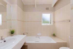 La salle de bains blanche est pourvue d'une baignoire et d'un lavabo. dans l'établissement San Lameer Villa 3502 by Top Destinations Rentals, à Southbroom