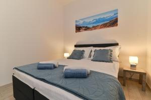 een slaapkamer met een groot bed met blauwe kussens bij Apartmani Castrum in Kaštela