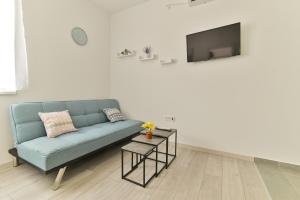 een woonkamer met een blauwe bank en een tv bij Apartmani Castrum in Kaštela