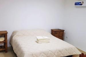 a white bed with two towels on top of it at Hermoso alojamiento temporario LA SOÑADA in Pigüé