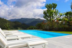 een groep witte ligstoelen naast een zwembad bij Casa Bela Vista in Geres