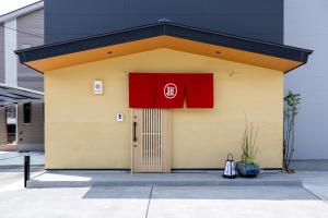 a building with a red sign on it at 【Oyado道】貸切露天風呂付！別荘感覚で新築一軒家まるごと貸し切り１日１組限定！ハウステンボス近く in Hayaki