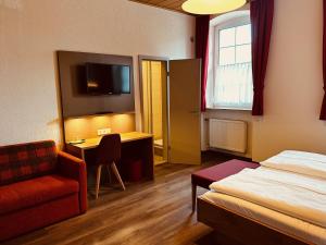 um quarto de hotel com uma cama, uma cadeira e uma escrivaninha em Hotel und Wirtshaus Löwen em Rielasingen-Worblingen