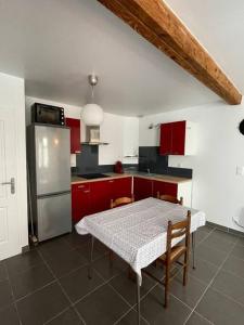 una cucina con armadi rossi, tavolo e frigorifero di Belle maison de ville rénovée a Lavardac