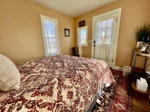 a bedroom with a bed with a flowered blanket at Violet Cottage at Zenzen Gardens in Paonia