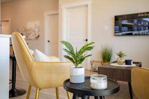 a living room with yellow chairs and a table with a plant at Brand new! Stylish 2 Bedroom Condo in Chatham