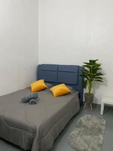 a bedroom with a bed with yellow pillows and a plant at Gemilang Guesthouse in Sungai Petani