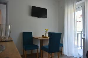 a room with two blue chairs and a table and a television at Apartmani Vila Ana in Gunjica