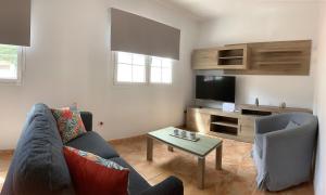 ein Wohnzimmer mit einem Sofa und einem TV in der Unterkunft Viviendas Vacacionales en el centro de Valleseco in Valleseco