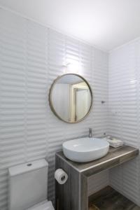a white bathroom with a sink and a mirror at Garden Apartment in Amarynthos I in Amarynthos