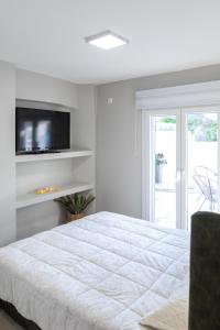 a white bedroom with a bed and a tv at Garden Apartment in Amarynthos I in Amarynthos