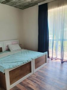 a bedroom with a bed and a window with curtains at Racha - ABA in Ambrolauri