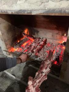 a person is cooking meat in a fireplace at Racha - ABA in Ambrolauri