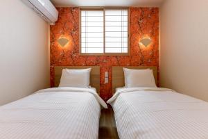 two beds in a room with a window at 【Oyado道】貸切露天風呂付！別荘感覚で新築一軒家まるごと貸し切り１日１組限定！ハウステンボス近く in Hayaki