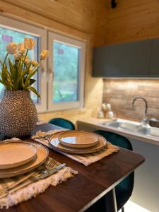 una cocina con una mesa con platos y un jarrón de flores en Elleria's House en Lefkada