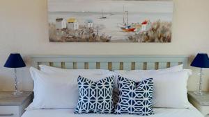 a bed with blue and white pillows and a painting at San Lameer Villa 2514 by Top Destinations Rentals in Southbroom
