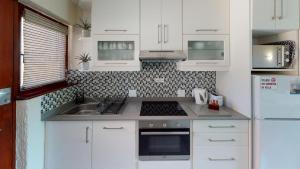a kitchen with white cabinets and a sink and a stove at San Lameer Villa 2514 by Top Destinations Rentals in Southbroom