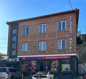 un edificio de ladrillo con coches estacionados frente a él en GS Hotel, en Tiflis