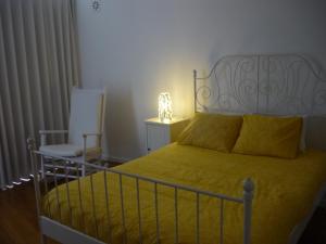 a bedroom with a bed with a yellow blanket and a chair at Casa da Terra in Góis