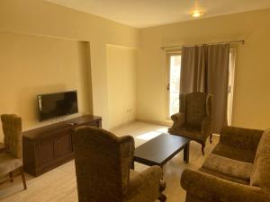 a living room with a couch and chairs and a tv at Bahga Palace 2 Residential Apartments in Hurghada