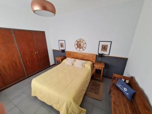 1 dormitorio con 1 cama con sábanas amarillas y armarios de madera en Aires del Roma en Pergamino