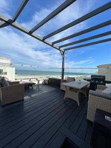 a deck with a table and chairs and the beach at Luxury apartment with sea view in Mamaia Sat/Năvodari