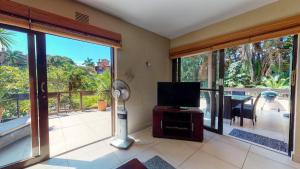 ein Wohnzimmer mit einem Flachbild-TV und großen Fenstern in der Unterkunft San Lameer Villa 3112 Top Destinations Rentals in Southbroom