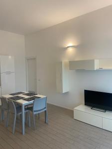 sala de estar con mesa, sillas y TV en Alba - Le Grotte Rooms & Apartments en Camerano