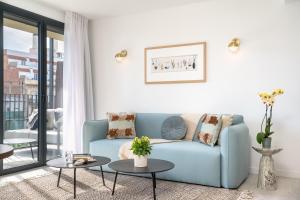 a living room with a blue couch and two tables at TSA La Rambla in Barcelona