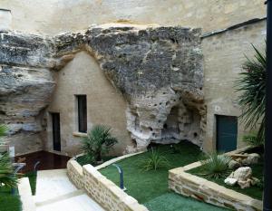 un edificio de piedra con una pared de roca y algunas plantas en La falaise perdue : Suite troglodyte grandiose en Doué-la-Fontaine
