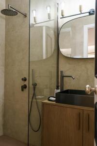 a bathroom with a shower with a sink and a mirror at Alkionides Hydra in Hydra