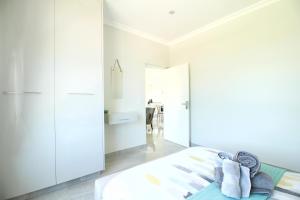 a bedroom with white walls and a bed with towels at Caribbean 1136 by Top Destinations Rentals in Port Edward