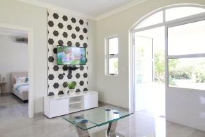 a white living room with a tv on a wall at Caribbean 1136 by Top Destinations Rentals in Port Edward