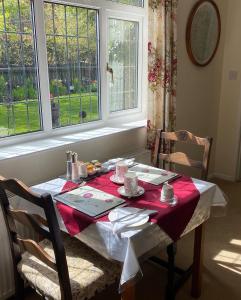 uma mesa com uma toalha de mesa vermelha e branca e duas janelas em Grove House Bed & Breakfast em York