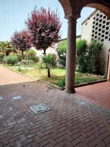une cour en briques avec un bâtiment et un arbre dans l'établissement Appartamento in cascina lombarda, à Caselle Lurani