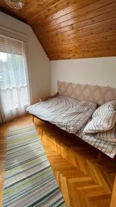 Cama grande en habitación con techo de madera en Vitorlás Haus, en Balatonkeresztúr