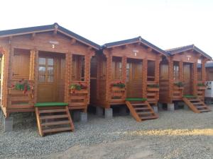a row of wooden cabins with benches in front at Căsuțe Suzanne Băile Figa-cu aer conditionat in Beclean