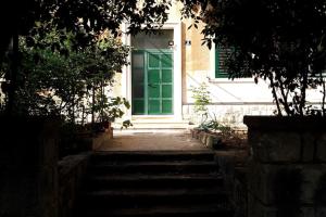 Una puerta verde en una casa con escaleras al frente. en Peacock Apartment, en Split