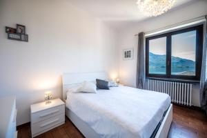 a bedroom with a white bed with a large window at Lake view apartment with balcony and parking - Larihome A25 in Gera Lario