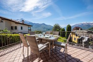 a table and chairs on a balcony with mountains at Lake view apartment with balcony and parking - Larihome A25 in Gera Lario