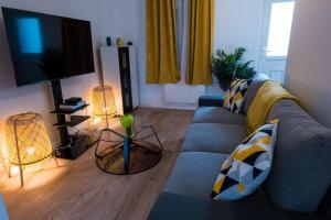 ein Wohnzimmer mit einem blauen Sofa und einem TV in der Unterkunft Chambre confortable à Rouen in Darnétal