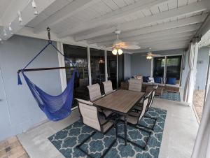 eine Veranda mit einer Hängematte sowie einem Tisch und Stühlen in der Unterkunft Blue Flamingo - Pool, Sunsets, Dock, Lift, Direct Gulf Access! in Cape Coral