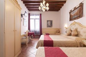 a bedroom with two beds and a desk and a chandelier at Alloggi SS Giovanni e Paolo in Venice