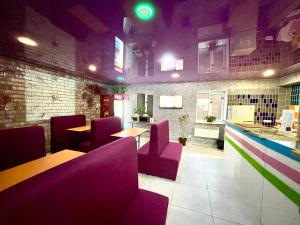 a restaurant with purple chairs and tables in a room at Sweet Home in Dnipro