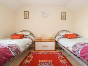 two twin beds in a room with a table at Curlews in Tintagel